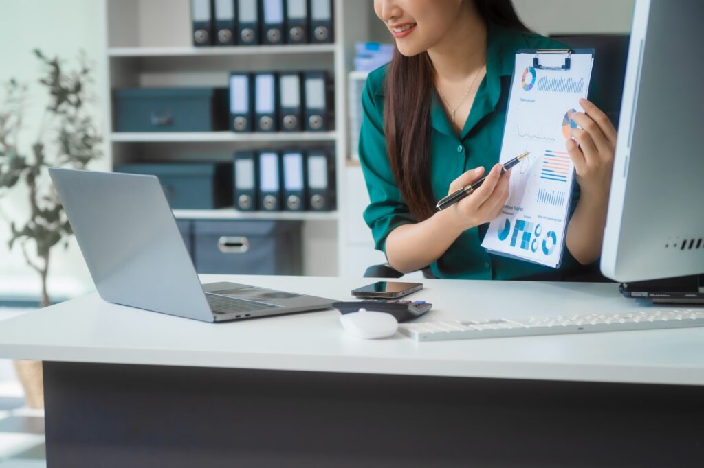Asian businesswoman in formal attire works on laptop, on corporate law and marketing strategy.