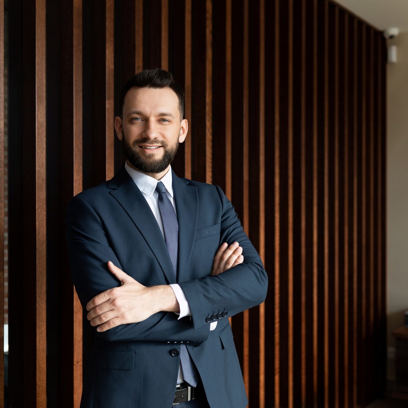 successful entrepreneur businessman in a strong office with his arms folded on his chest looks at